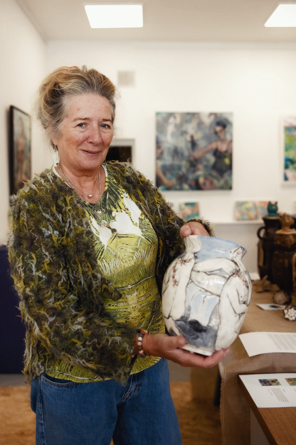 a woman shows a decorated amphora to the camera