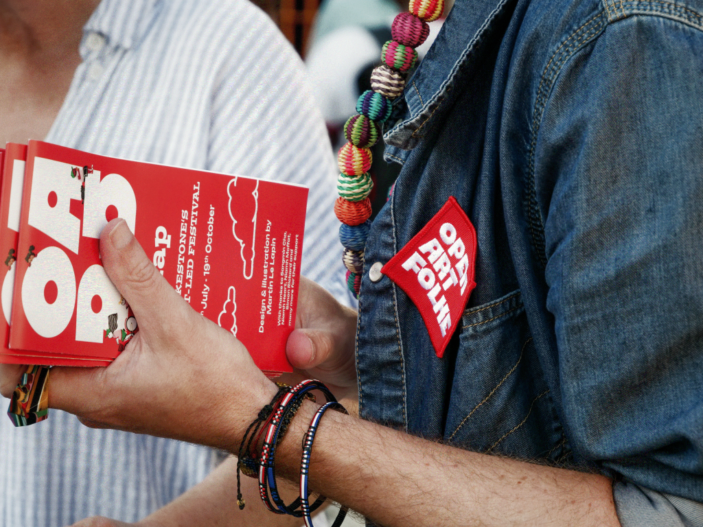 Person holds several red, "Open Art Folke" maps