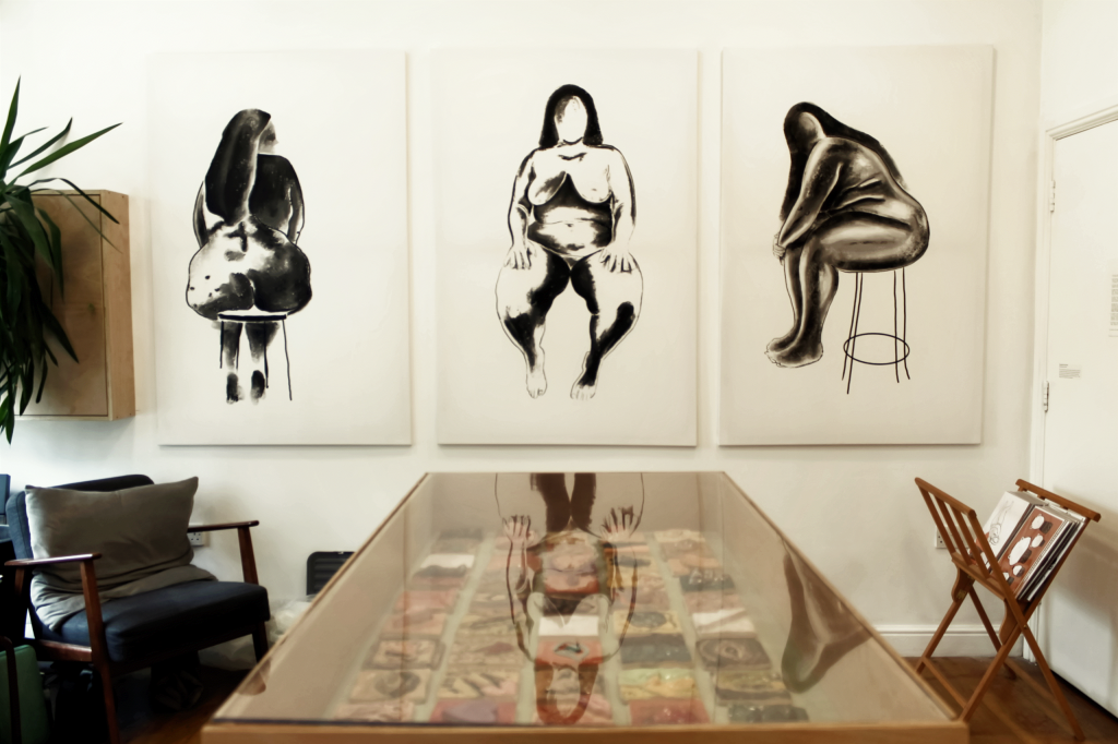 a triptych of paintings in black ink on white canvas represent bodies of fat women